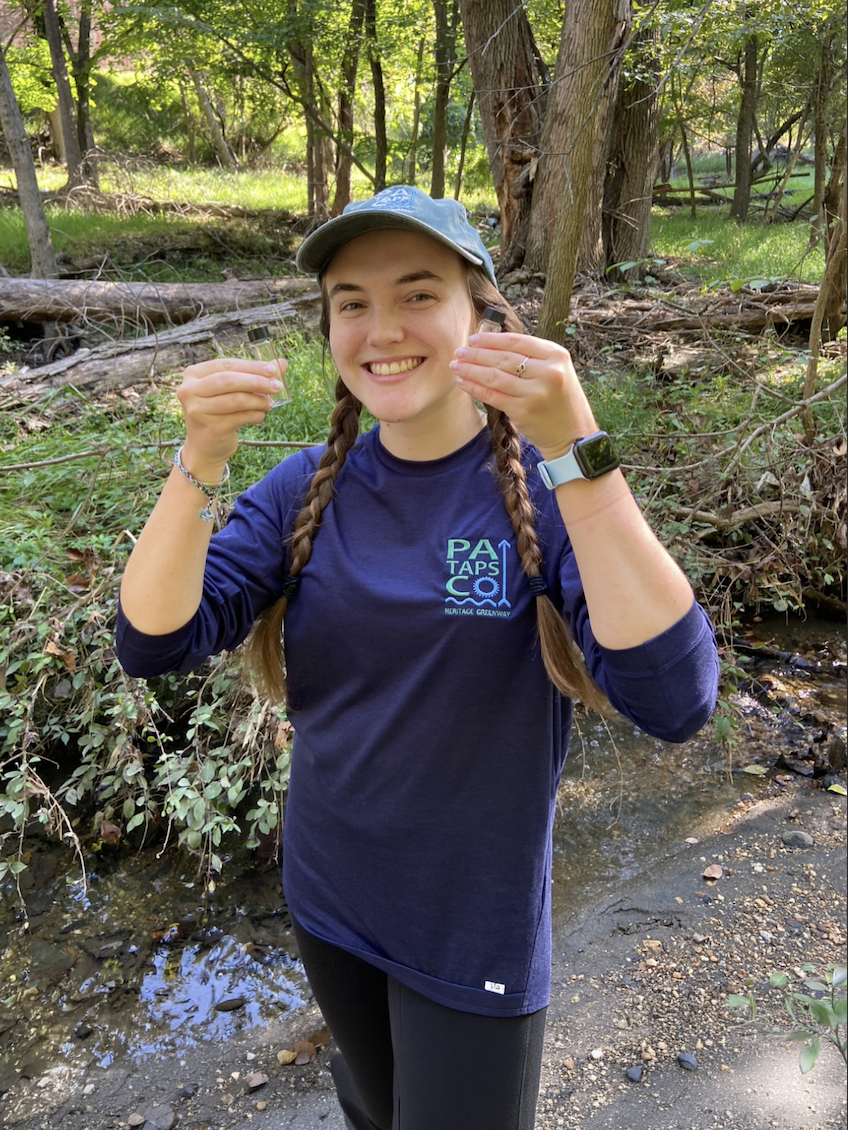woman with braids smiling in forest with glass vials